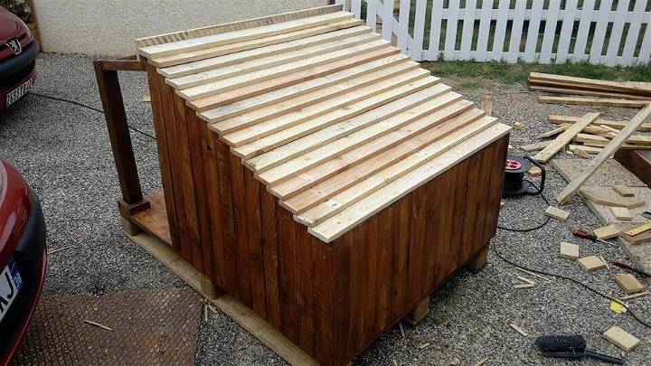 wooden pallet dog house with shingled tilted roof